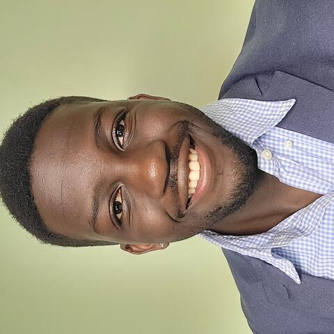 Man in a blue suit smiling in front of a green background